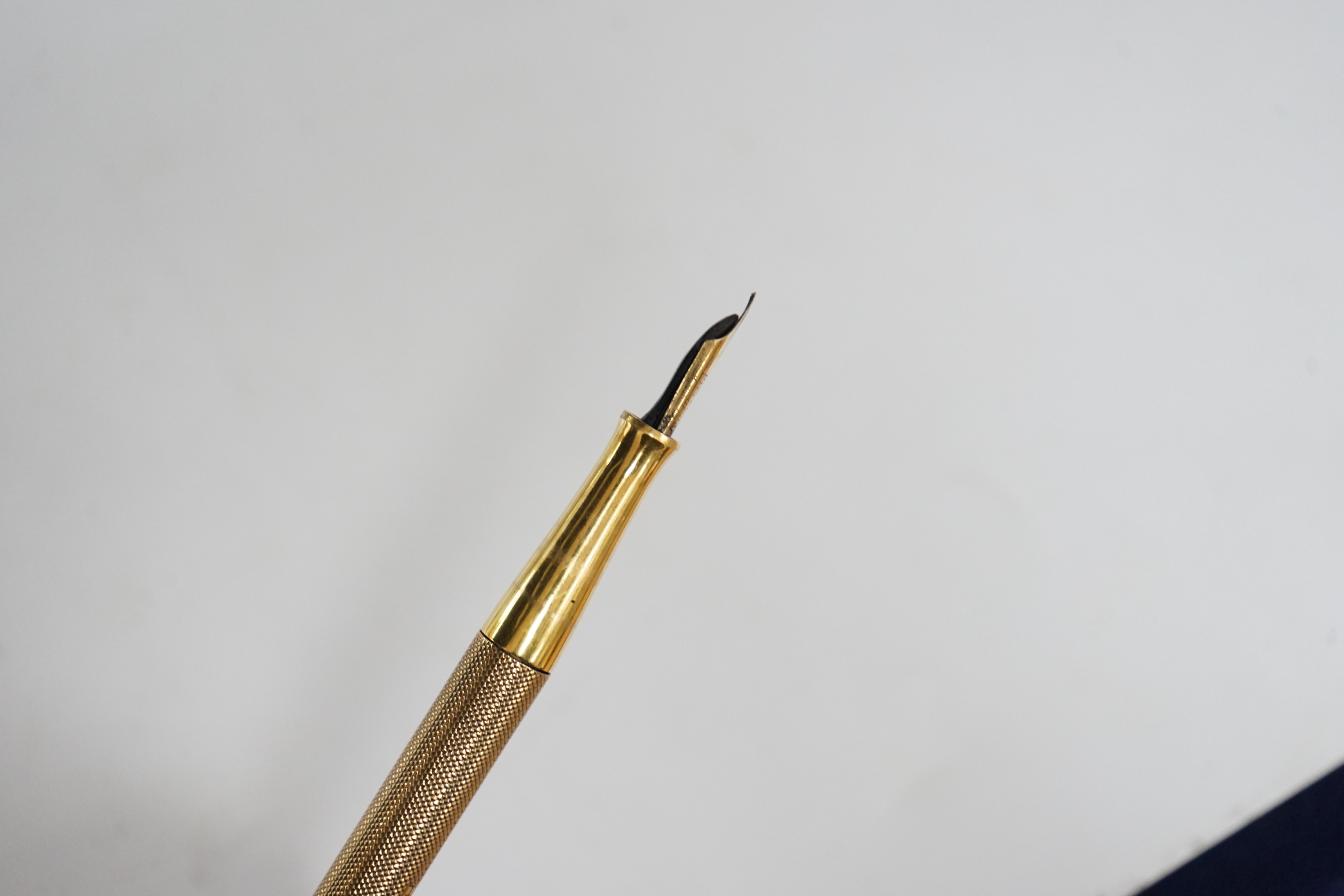 A George V engine turned 9ct. gold combination fountain pen and pencil, with holder (once attached to a stand), maker F.D.W. London, 1935, 20.4cm.